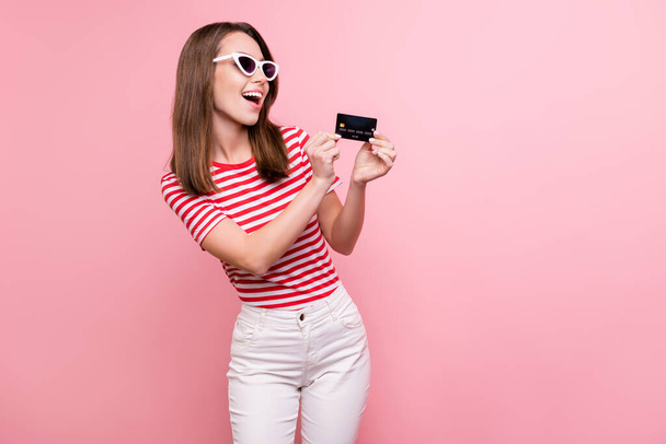 Photo of young girl happy positive smile look credit card salary money profit isolated over pink color background. - Foto, imagen