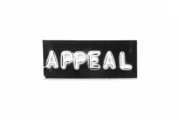 Banner de color negro que tiene carta en relieve con apelación de palabra sobre fondo de papel blanco - Foto, imagen