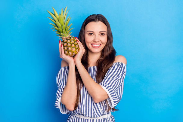 Photo of pretty charming young woman dressed striped outfit smiling holding fruit isolated blue color background. - Zdjęcie, obraz