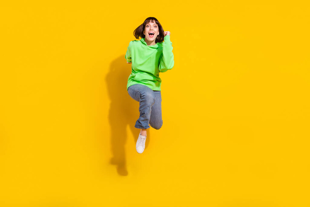 Full length body size view of attractive cheerful girl jumping running marathon isolated over bright yellow color background. - Фото, изображение