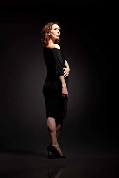 High fashion portrait of elegant woman in long black dress. Over Black background - Foto, Imagem