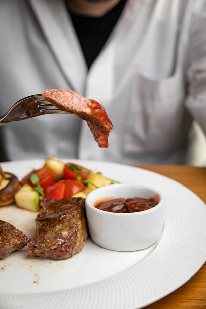 Steak with garnish and sauce on a plate - Zdjęcie, obraz