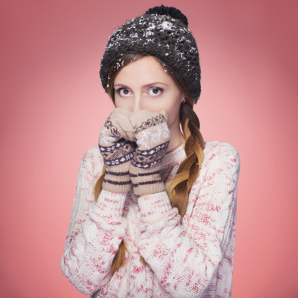 Hermosa mujer pelirroja en traje de invierno: suéter caliente, bufanda y sombrero con nieve por todas partes. Aislado en rojo rosado
 - Foto, imagen
