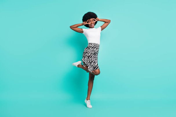 Photo of funny charming dark skin lady wear casual clothes walking v-signs cover eyes smiling isolated teal color background. - Φωτογραφία, εικόνα