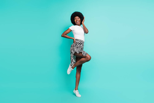 Photo of funny impressed dark skin lady wear casual clothes smiling dancing isolated teal color background. - Foto, imagen