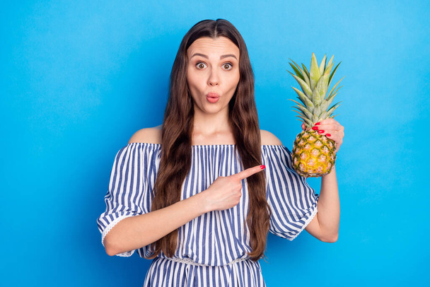 Photo of hungry excited young lady wear off-shoulders clothes pointing finger pineapple big eyes isolated blue color background. - Фото, изображение