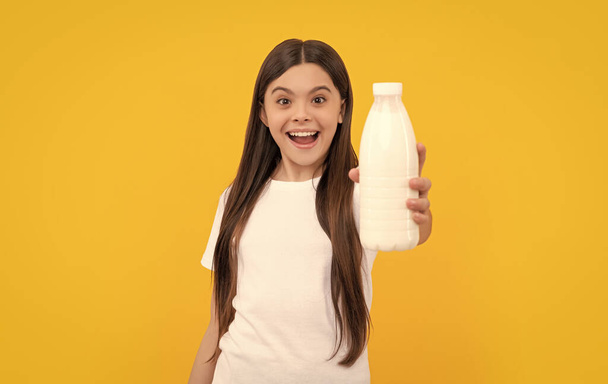 Hayretler içindeki çocuk süt ürünlerini elinde tutuyor. Kız süt içecek. Sağlıklı bir yaşam tarzı. Çocukluk gıdası. Günde bir içki. Süt ürünleri. Kahvaltıda yoğurt. Çocuk süt şişesini tutuyor. seçici odak. - Fotoğraf, Görsel