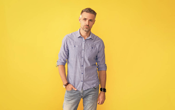 volwassen man met horloge op gele achtergrond, mode-accessoire. - Foto, afbeelding