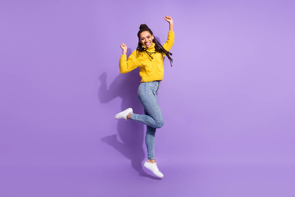 Full size photo of impressed brunette lady jump wear yellow sweater jeans sneakers isolated on purple color background. - Foto, immagini