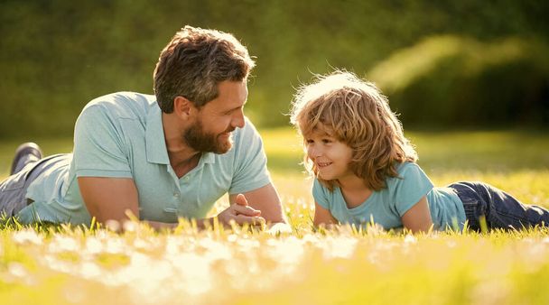 onnellinen perhe isä ja poika poika rentoutua kesäpuistossa vihreä ruoho, ystävyys. - Valokuva, kuva