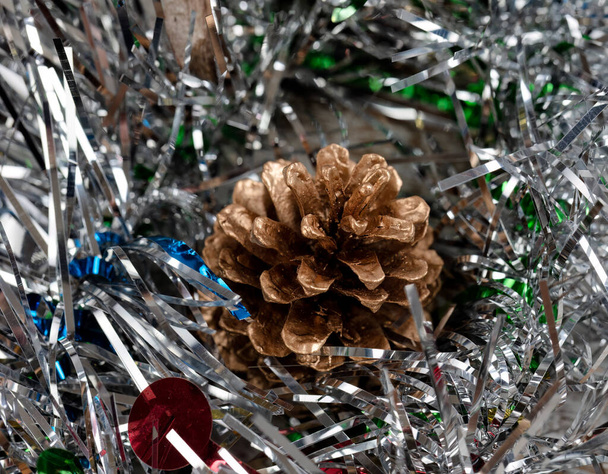 Gros plan d'un seul cône de pin doré en tinsel d'argent pour la période des fêtes de Noël ou du Nouvel An  - Photo, image