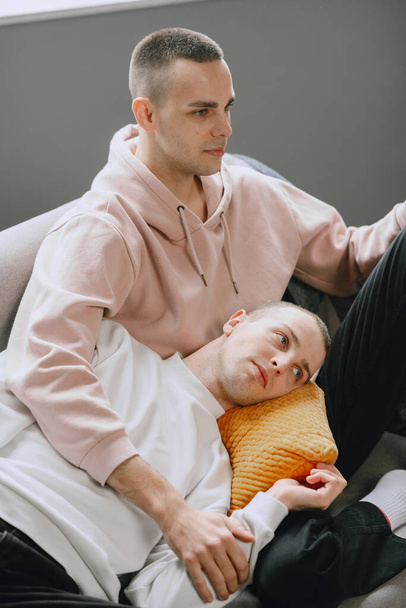 Young romantic gay couple spending day cuddling and relaxing on the couch. Different family lifestyle concept. - Fotografie, Obrázek