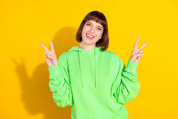 Photo of happy cheerful nice young woman make v-signs smile good mood isolated on yellow color background. - Valokuva, kuva