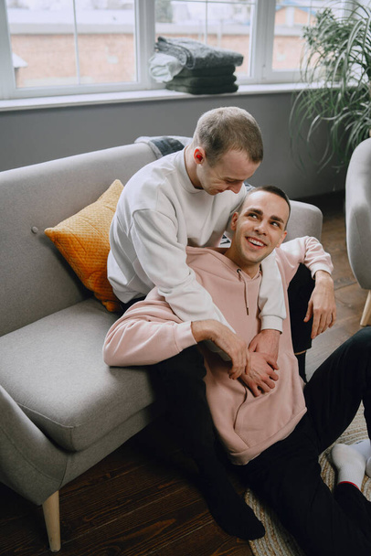 Young romantic gay couple spending day cuddling and relaxing on the couch. Different family lifestyle concept. - Fotoğraf, Görsel