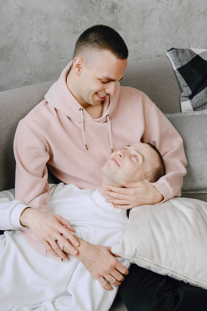 Young romantic gay couple spending day cuddling and relaxing on the couch. Different family lifestyle concept. - Foto, Bild