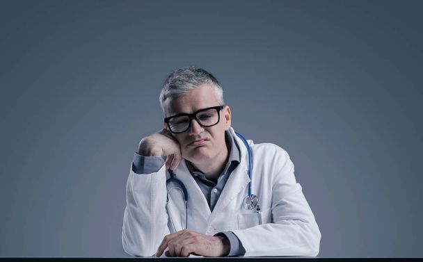 Disappointed sad doctor leaning on his arm, he feels hopeless and confused - Foto, imagen