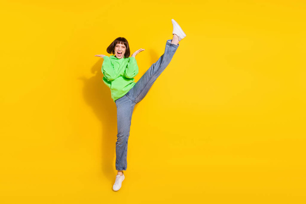 Full length photo of attractive young woman jump up good mood raise leg isolated on yellow color background. - Fotografie, Obrázek
