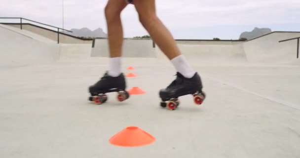 Closeup rearview of a man roller skating for hobby around cones at a skate park. Having fun on wheels, showing skills and feeling carefree. Practicing and learning how to roller blade outside. - Footage, Video