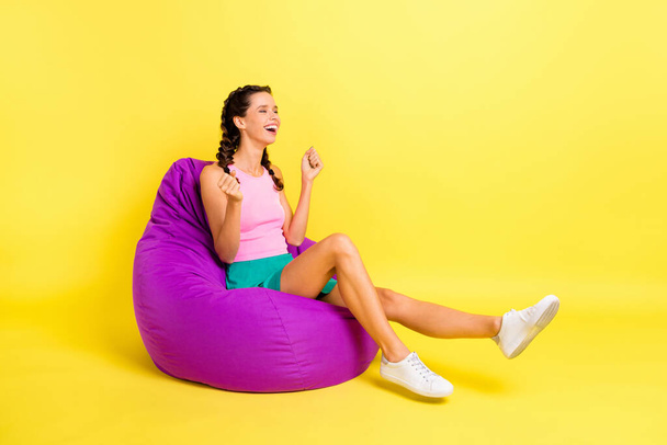 Full length profile side photo of victorious woman raise fists sit bean bag isolated on shine yellow color background. - Valokuva, kuva