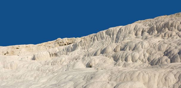 Landscape of the Travertine pools and terraces in Pamukkale Turkey. Desert sand with textured pattern against a blue sky. Tourism holiday destination at rock cotton castle location during hot springs. - Photo, Image