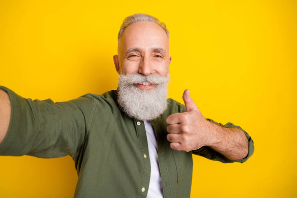 Photo portrait of grandfather taking selfie on camera smiling showing like sign isolated vivid yellow color background. - Fotó, kép