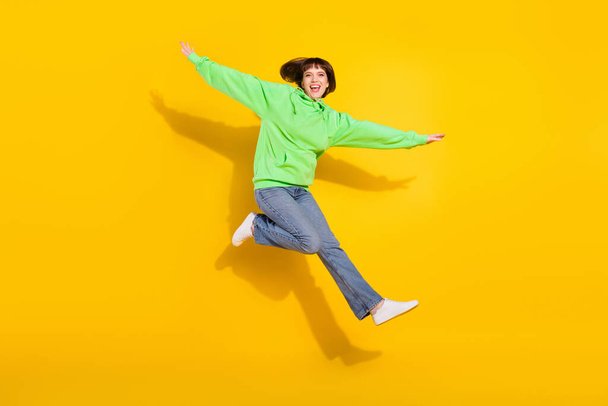 Full size foto van vrolijke jonge vrolijke leuke vrouw springen goede doom handen vleugels geïsoleerd op gele kleur achtergrond. - Foto, afbeelding