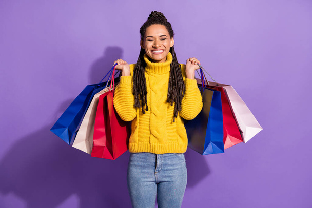 Photo of impressed brunette lady hold bags wear yellow sweater isolated on purple color background. - Фото, изображение