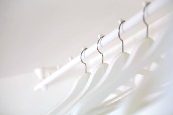 White wooden hangers hang on the crossbar on a white background. - Foto, Imagem