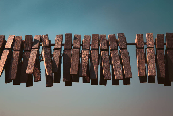 A closeup shot of wooden clothespins on a rope - Fotó, kép