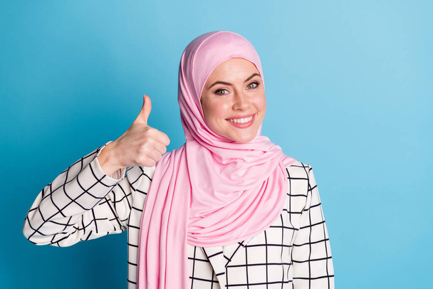 Close-up portrait of nice cheerful confident muslimah girl showing thumbup isolated over vivid blue color background. - Φωτογραφία, εικόνα