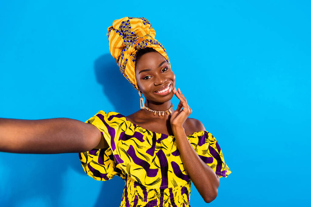 Photo of happy cheerful lovely beautiful african woman in turban taking selfie isolated on blue color background. - Photo, image