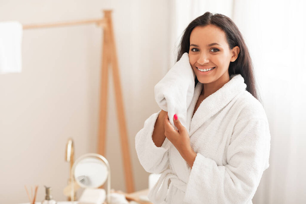 Glückliche Dame Trocknen Gesicht mit weichem Handtuch Pflege für perfekte Haut posiert lächelnd Blick auf Kamera im modernen Badezimmer zu Hause. Schönheitspflege Routine und Gesichtspflegekonzept - Foto, Bild