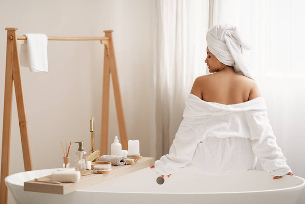 Küvette oturan tanınmayan bir kadın evde modern banyoda banyo yaptıktan sonra vücut bakımının ve güzellik rutininin tadını çıkarıyor. Spa ve Sağlık Konsepti - Fotoğraf, Görsel