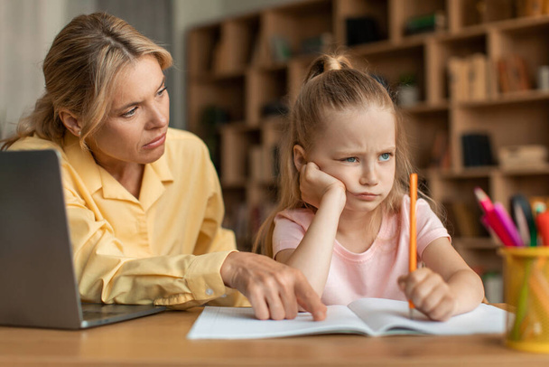 Strict mother scolding upset daughter for bad marks or school exam results, mum lecturing unmotivated girl, pointing to notebook. Generations, parent and child conflict - 写真・画像