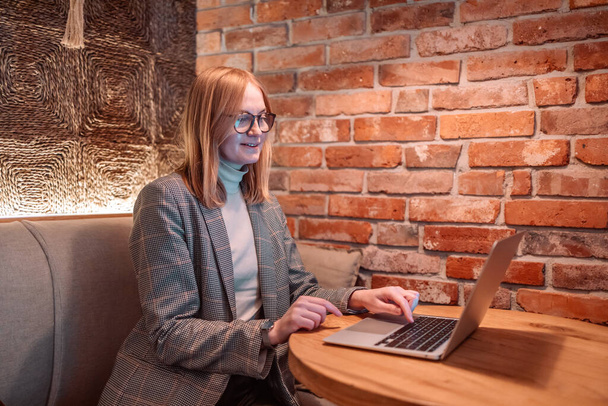 Retrato de una mujer seria de 30 años con pantalla blanca maqueta portátil de trabajo y navegar por la web en el escritorio en la cafetería - Foto, imagen
