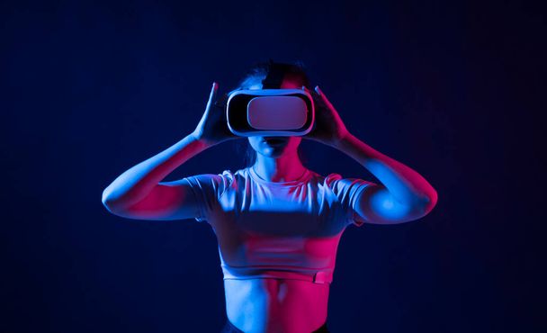 Uma menina bonita em 3D óculos de realidade virtual gosta de viagem em um mundo aventureiro no escritório. Ação feminina em capacete realidade virtual. Dispositivo de RV digital. Um conceito de web global - Foto, Imagem