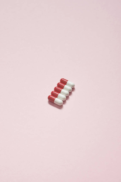 Red and white pharmaceutical tablets neatly laid over pink background. Flat lay with copy space. - Photo, image