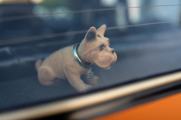 Pes maskot přikyvující na polici ve starém autě za oknem - Fotografie, Obrázek
