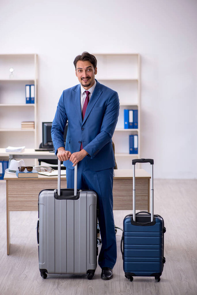 Young businessman employee preparing for trip at workplace - Foto, afbeelding