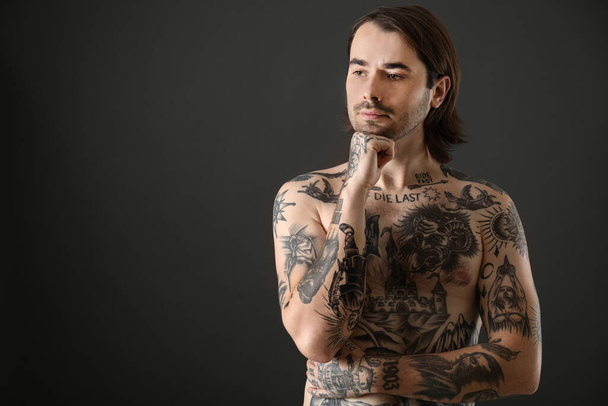 Young man with tattoos on body against black background. Space for text - Foto, Bild