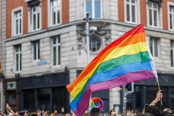 Różnorodni ludzie chodzą po paradzie gejowskiej dumy po ulicach miasta z flagami. Wysokiej jakości zdjęcie - Zdjęcie, obraz