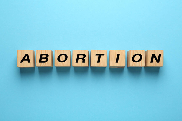 Word Abortion made of wooden cubes on light blue background, flat lay - Photo, Image