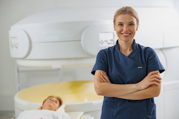 Dokter radioloog op achtergrond van MRI of CT scan met patiënt. Hoogtechnologische medische apparatuur - Foto, afbeelding