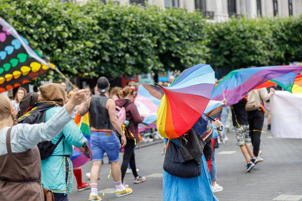 Diversas personas están caminando en un desfile de orgullo gay en las calles de la ciudad con banderas. Foto de alta calidad - Foto, Imagen