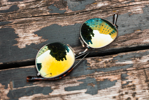 Fashionable chameleon sunglasses on a wooden background. view from above - Valokuva, kuva