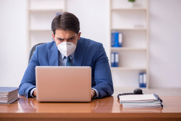 Joven empleado masculino que trabaja en la oficina durante una pandemia - Foto, imagen