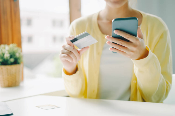 Close up woman using credit card for purchasing and shopping online on smartphone. - 写真・画像