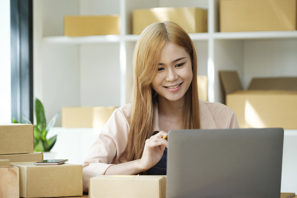 Online small business owner writing address on parcel box for delivery to customer, shipping and logistic, merchant online and seller, business owner or SME, online shopping. - Photo, Image