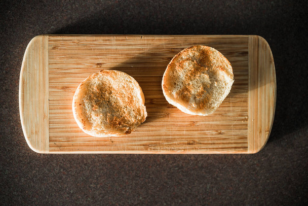 freshly toaste English muffins on cutting board shot under harsh sunlight, concept of simple natural healthy ingredients - Photo, image
