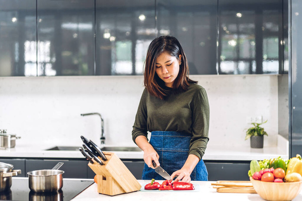 Retrato de sonriente profesional guapo asiático mujer chef cocina y la preparación de ensalada con comida de cocina en el mostrador de pie en el restaurante cocina comercial - Foto, imagen